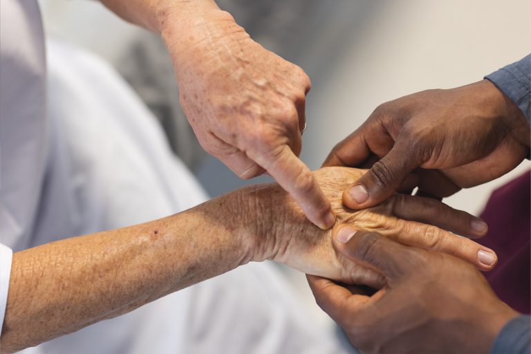 Nahaufnahme der manuellen Lymphdrainage durch einen Physiotherapeuten an den Handinnenflächen eines älteren Mannes