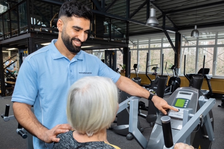 Physiotherapeut Golab vom Physio-Point in Hamburg leitet eine ältere Patientin beim Training auf einem Gerät im Medizinischen Fitnesscenter an